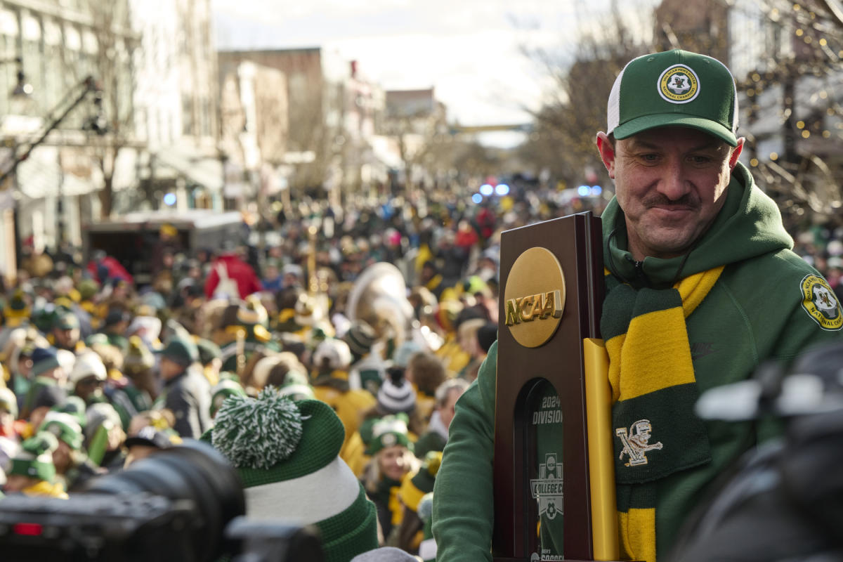UVM Men's Soccer Coach holds National Championship trophy on Church Street