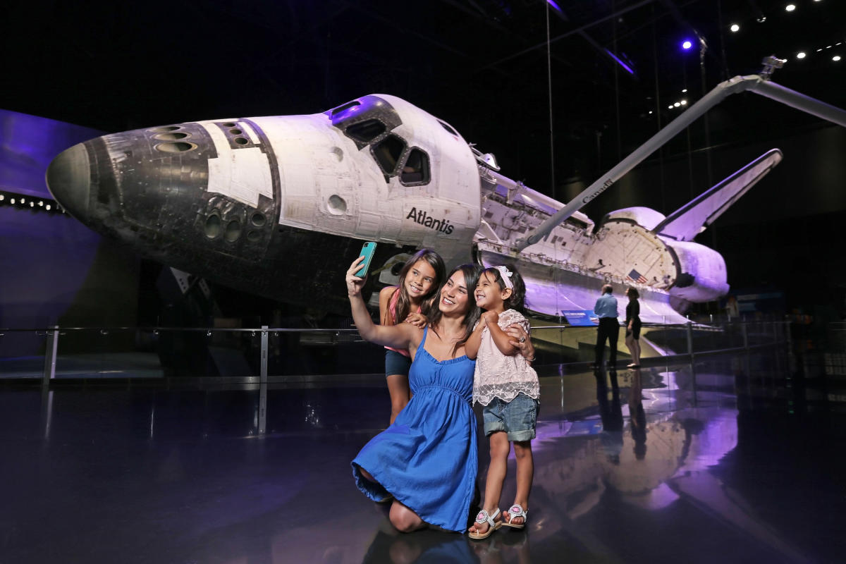 a family takes their selfie by the Atlantis Space Shuttle