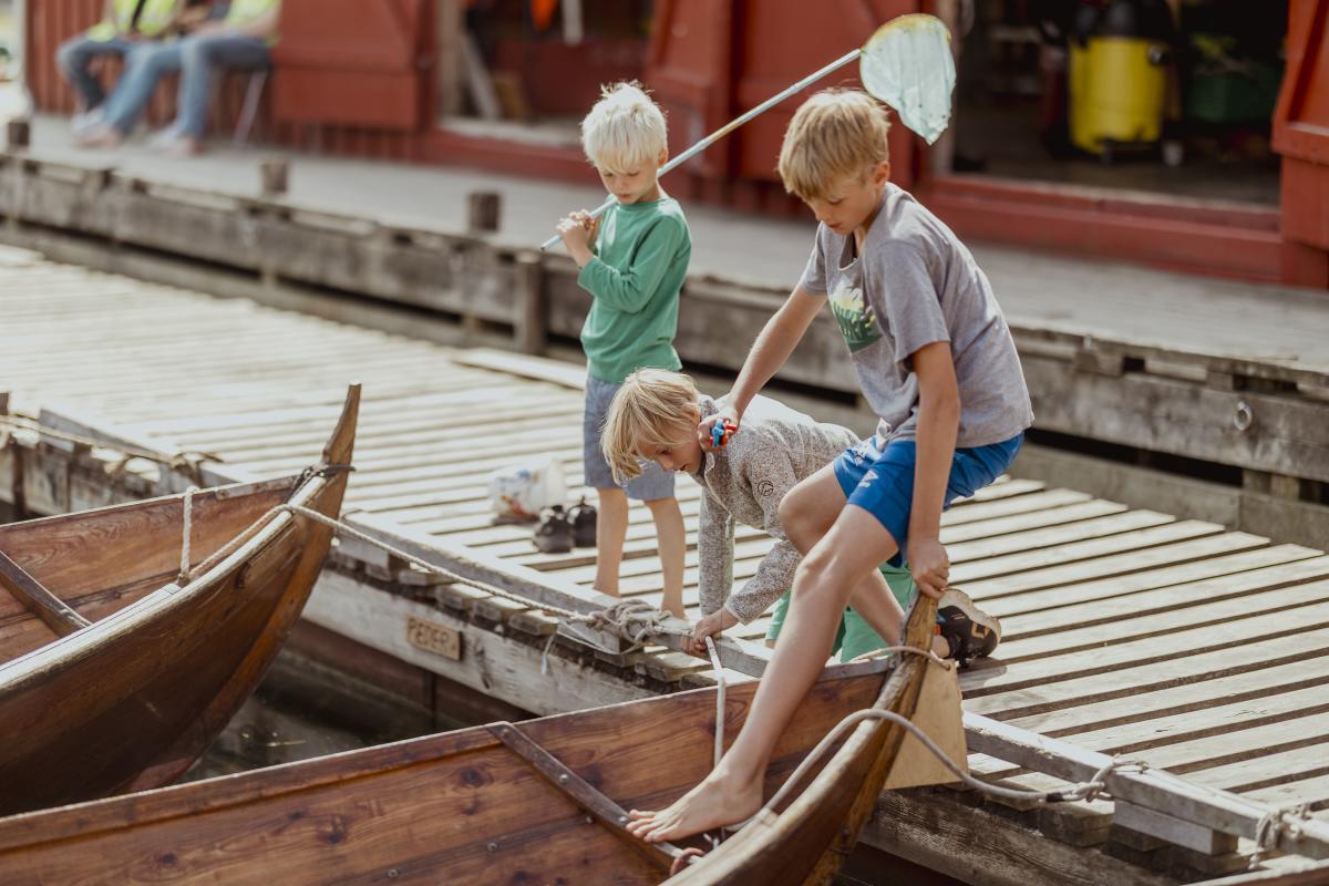 Barn fisker etter krabber fra robåter