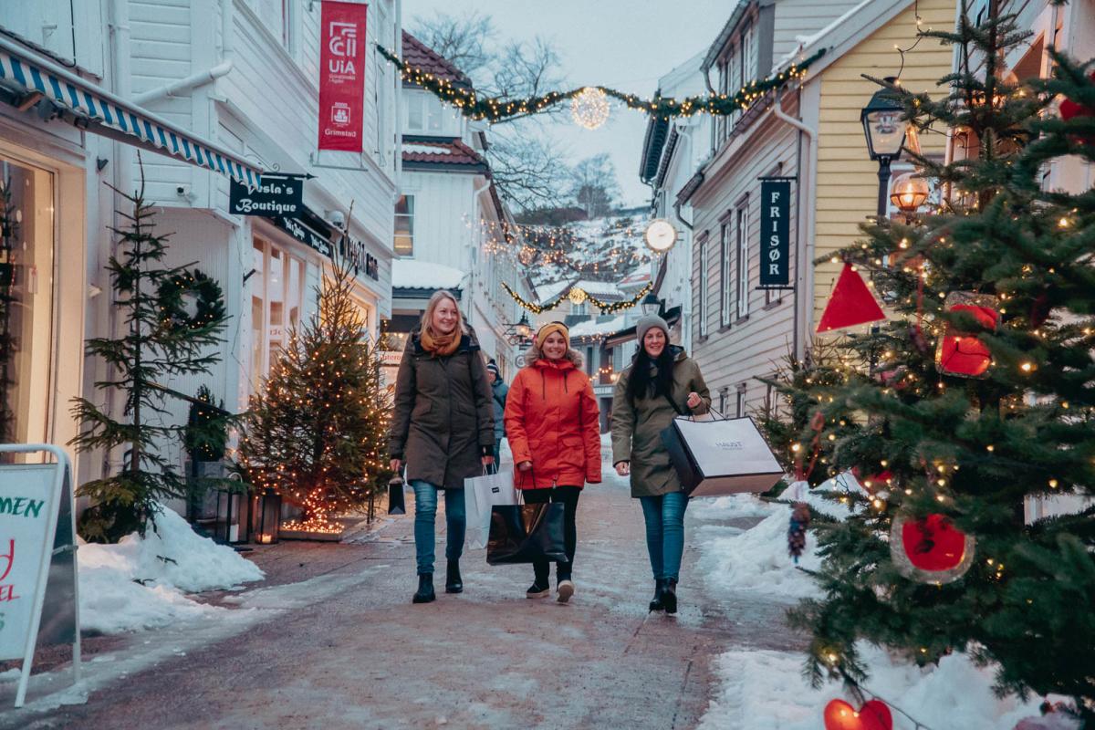 Julestemning i gågata i Grimstad med snø, julelys  og juletrær.