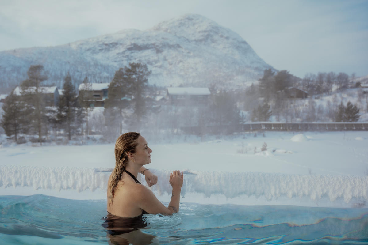 Kvinne ser utover vinterlandskap fra en varm akvedukt