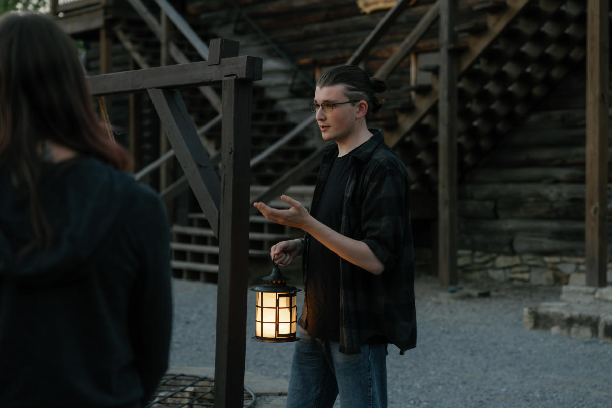 A man holding a lantern and telling ghost stories at Fort William Henry Museum