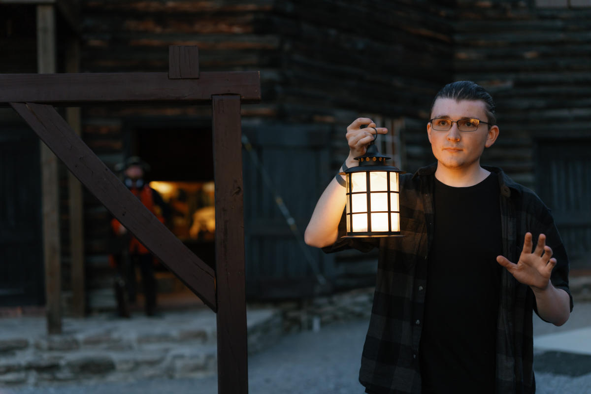 A man holding a lantern and telling ghost stories at Fort William Henry Museum