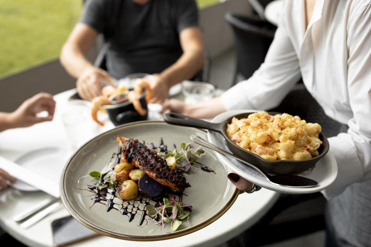 A waitress serves two plates of food to a table.