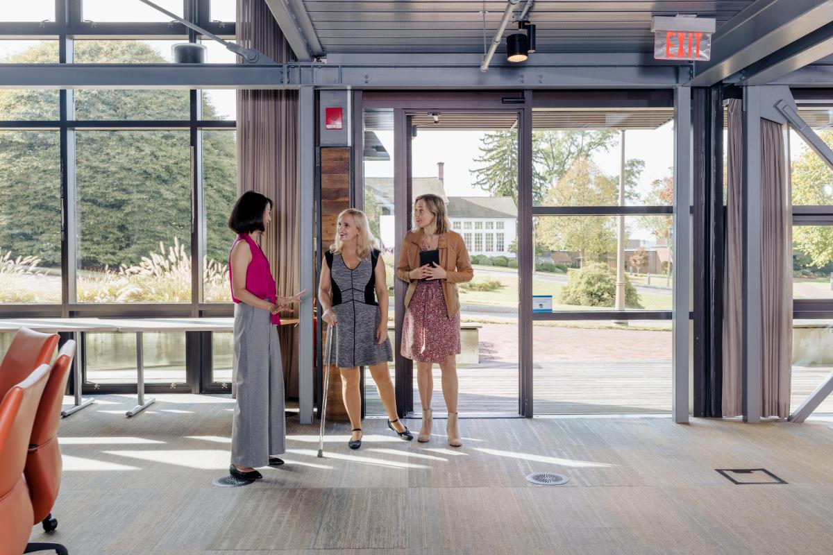 Two women tour a meeting facility with a guide.