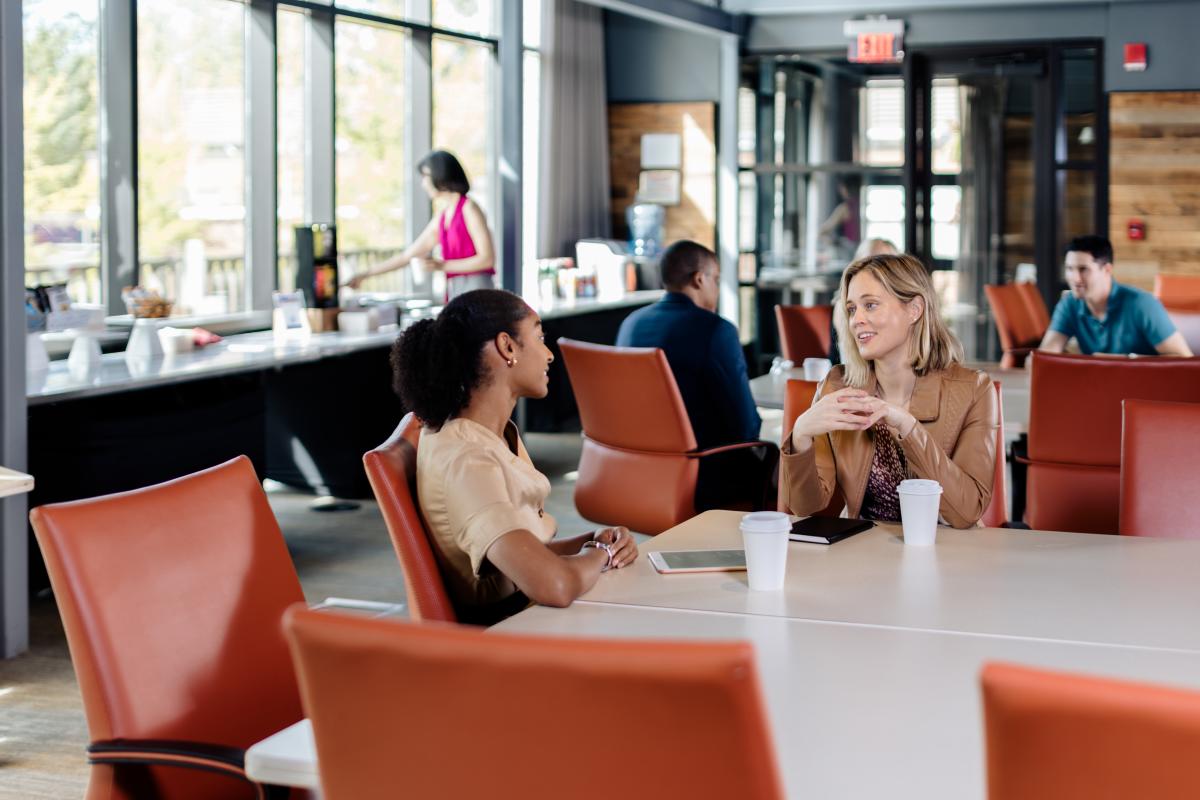 Two women sit together at a table enjoying a cup of coffee.