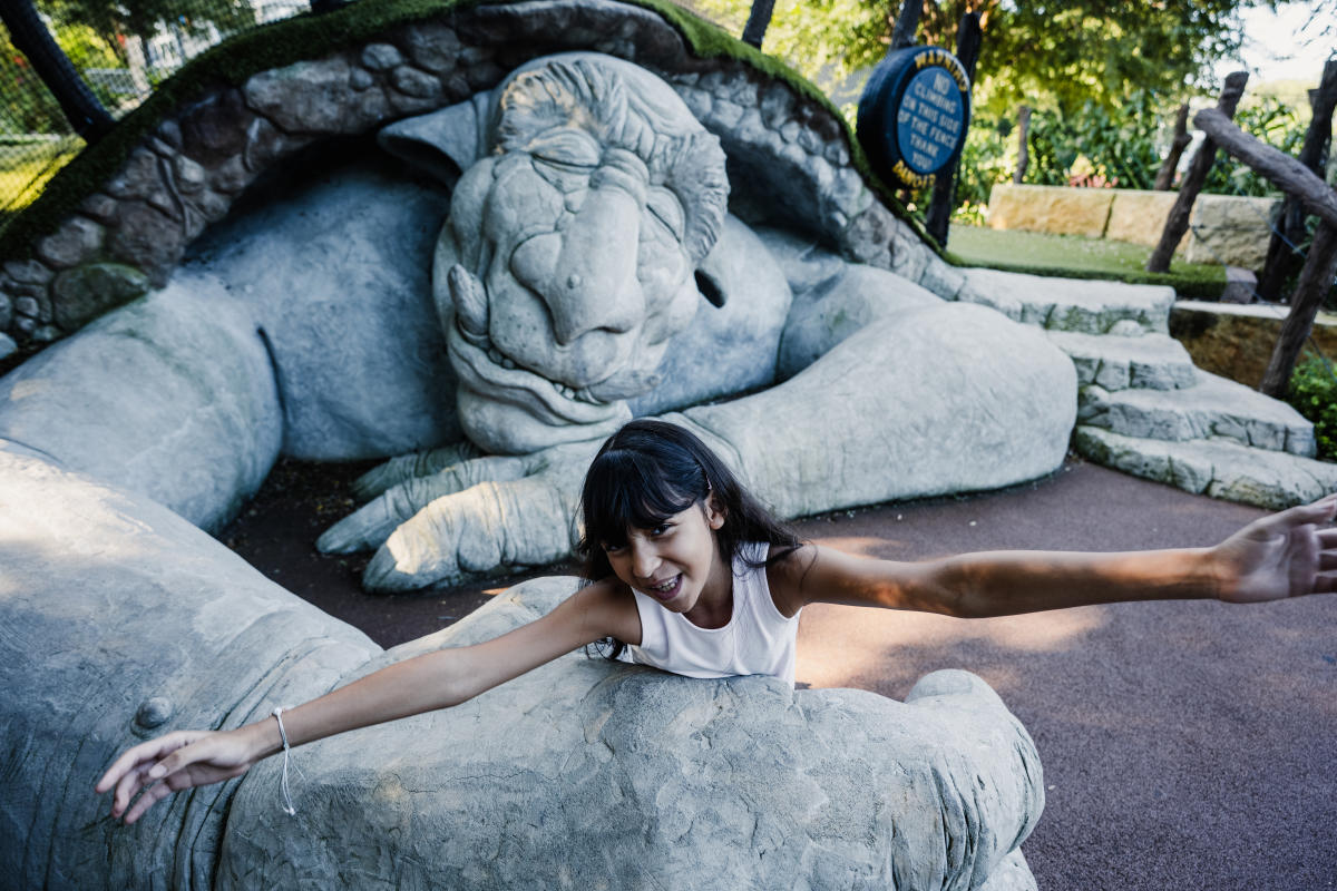 A girl poses in the arms of a giant troll statue at Botanica Wichita