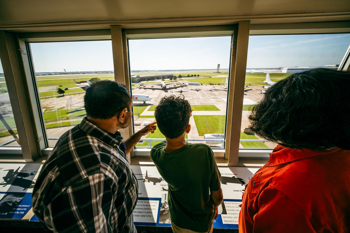 A family looks out the glass of the air traffic control tower at Kansas Aviation Museum.