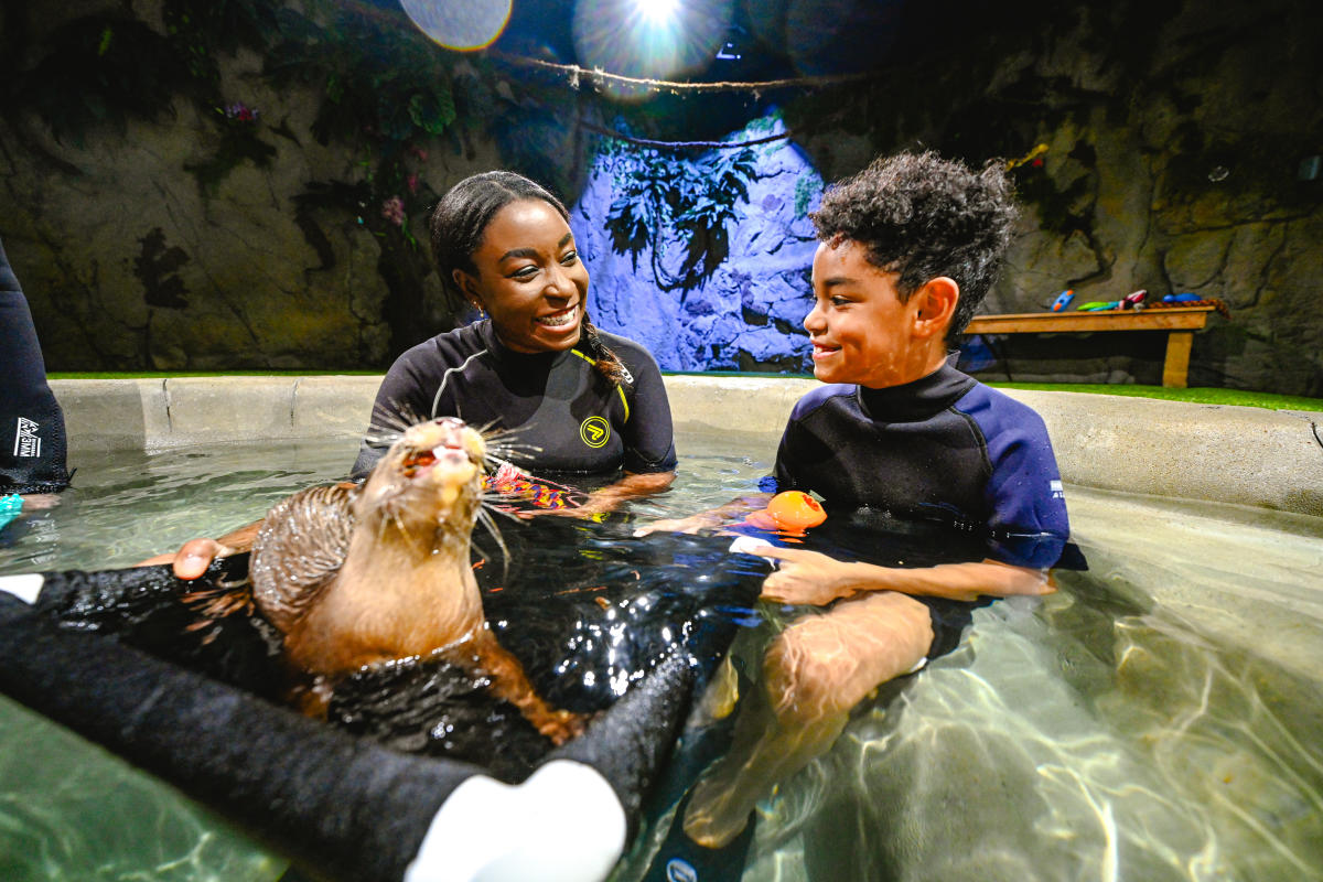 A boy and girl smile at each other while swimming with otters at Tanganyika Wildlife Park in Wichita.