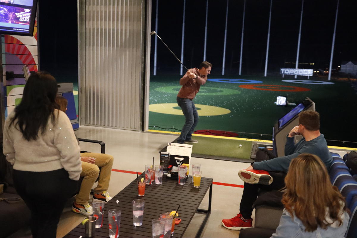 A group of young adults enjoy drinks and golf at Topgolf Wichita