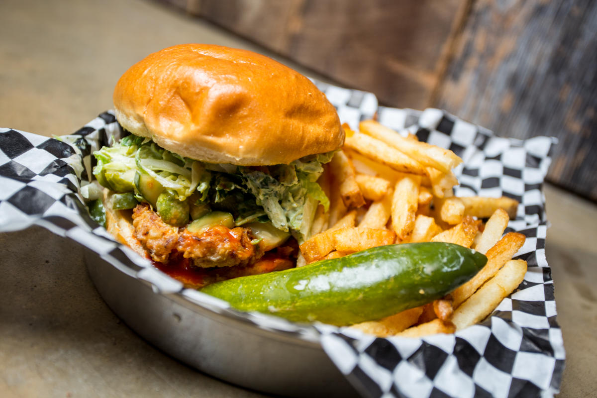 A fried chicken sandwich is served with fries and a pickle at Chicken N Pickle