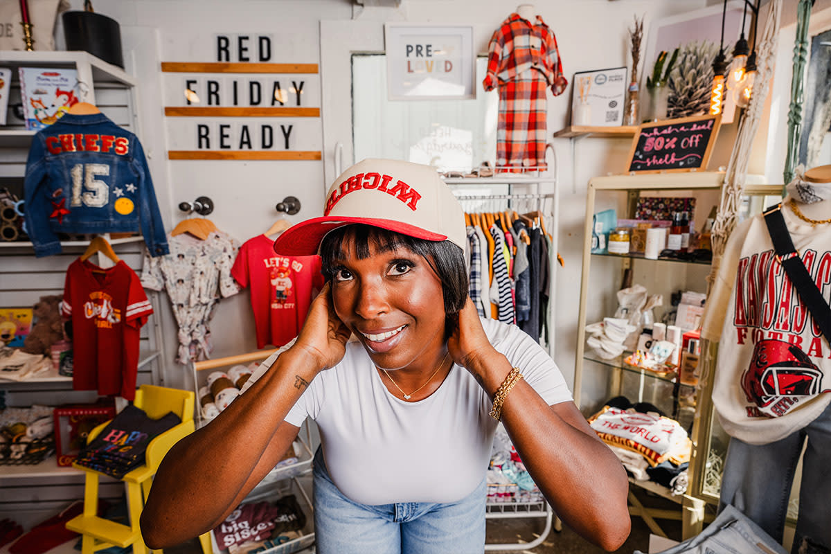A woman smiles while trying on a Wichita ballcap at Clifton Collective in Wichita.