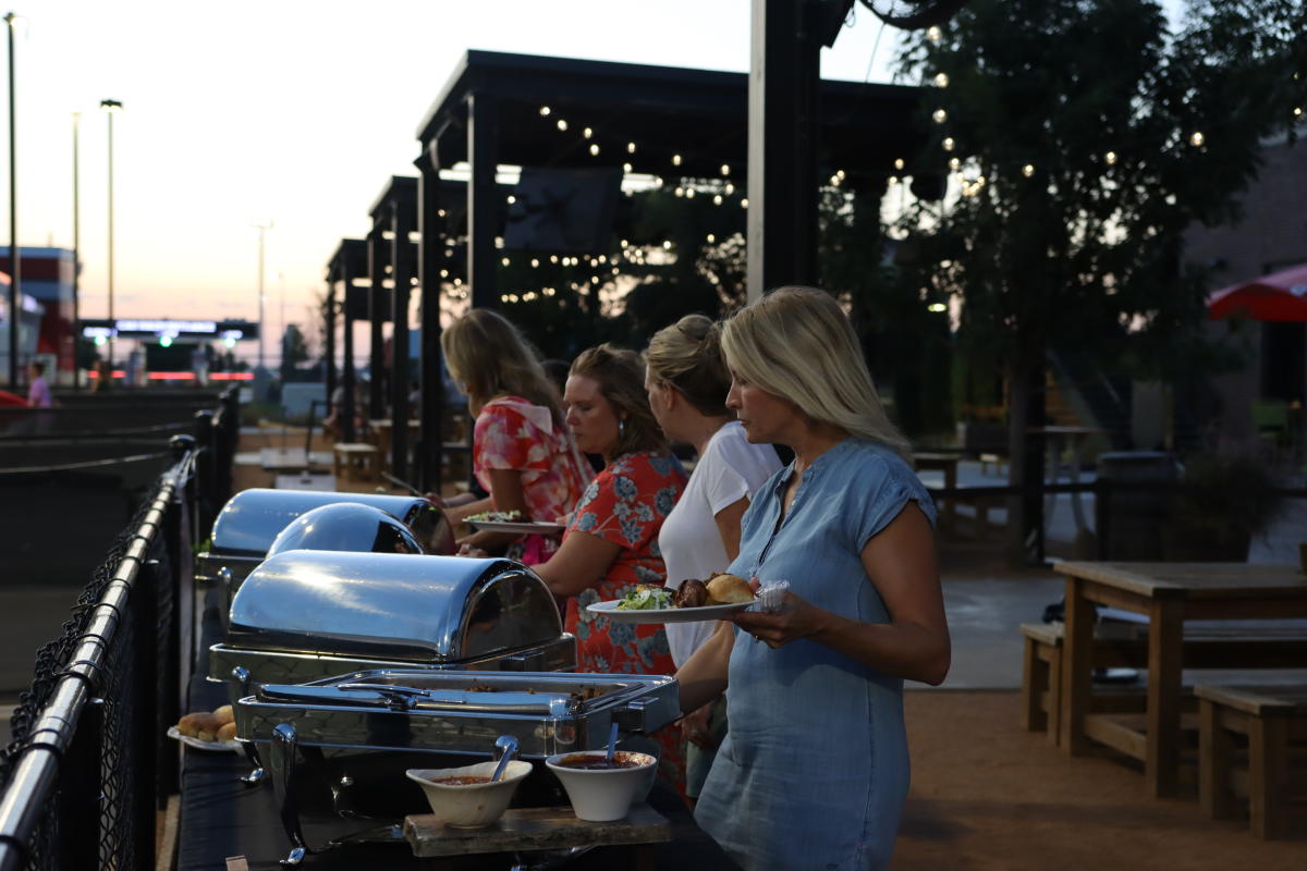 Meeting attendees get food from a buffet line outside at Chicken N Pickle