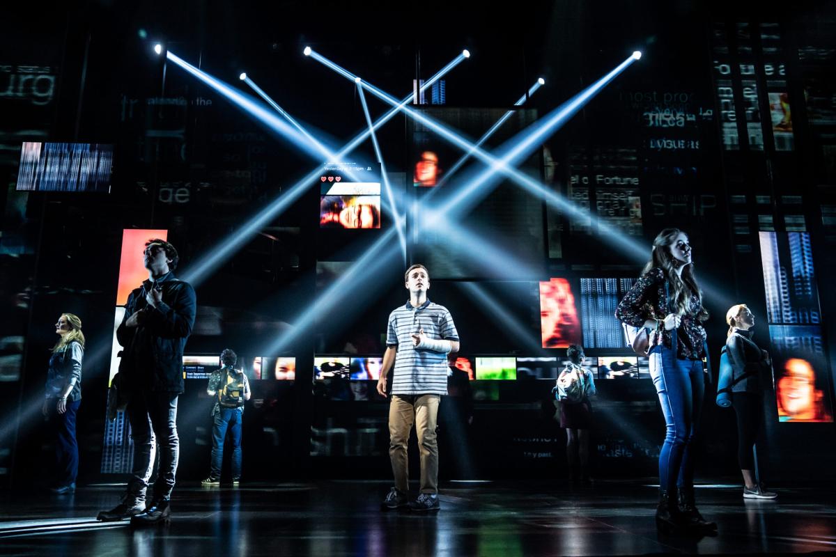 Cast members perform under bright lights during a scene in the musical Dear Evan Hansen