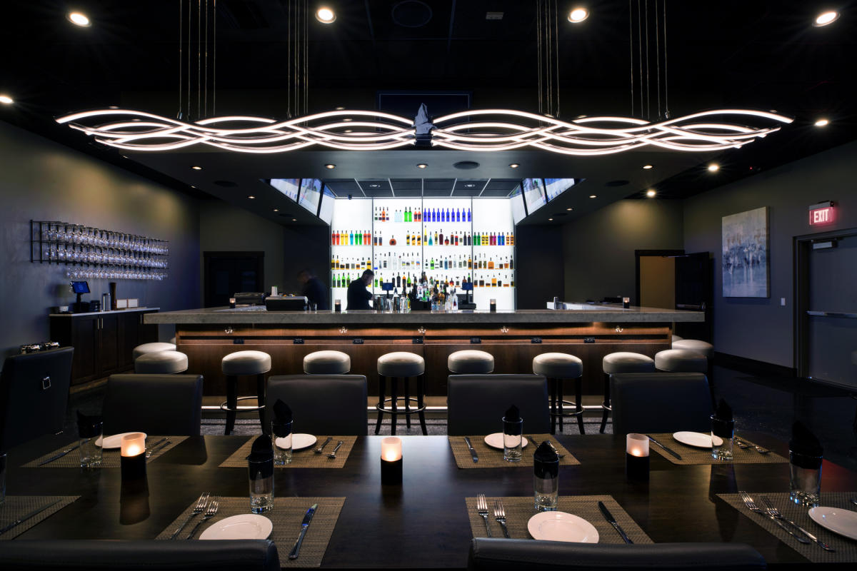 A bartender prepares for the dinner crowd behind the bar in the dining room of 6S Steakhouse