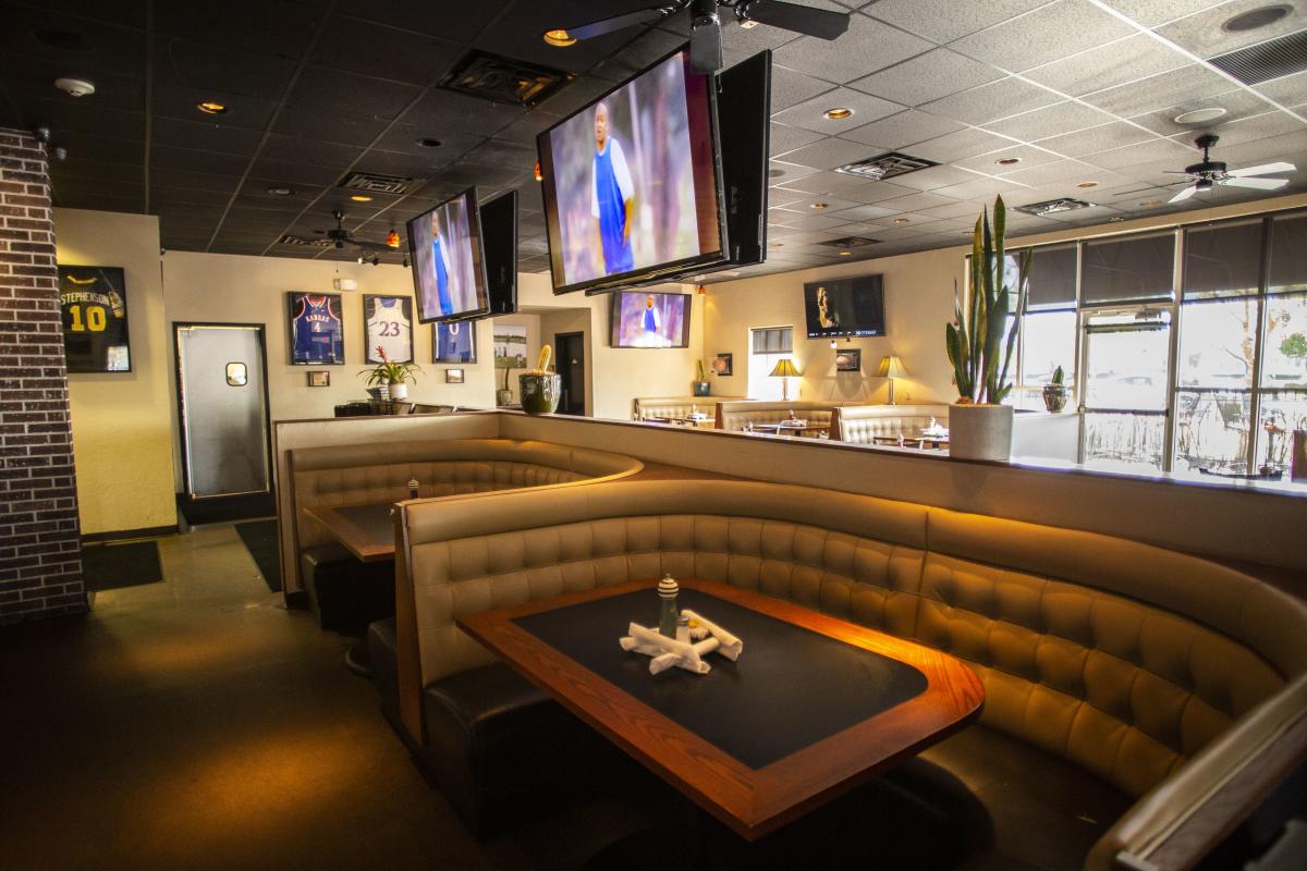 A large booth sits empty under large TV's inside of Deano's in Wichita
