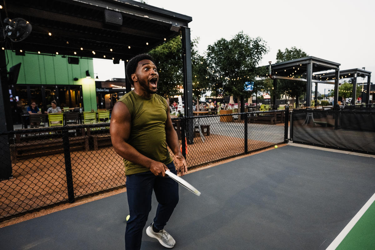 A man smiles with his mouth wide open in surprise while playing pickleball at Chicken N Pickle