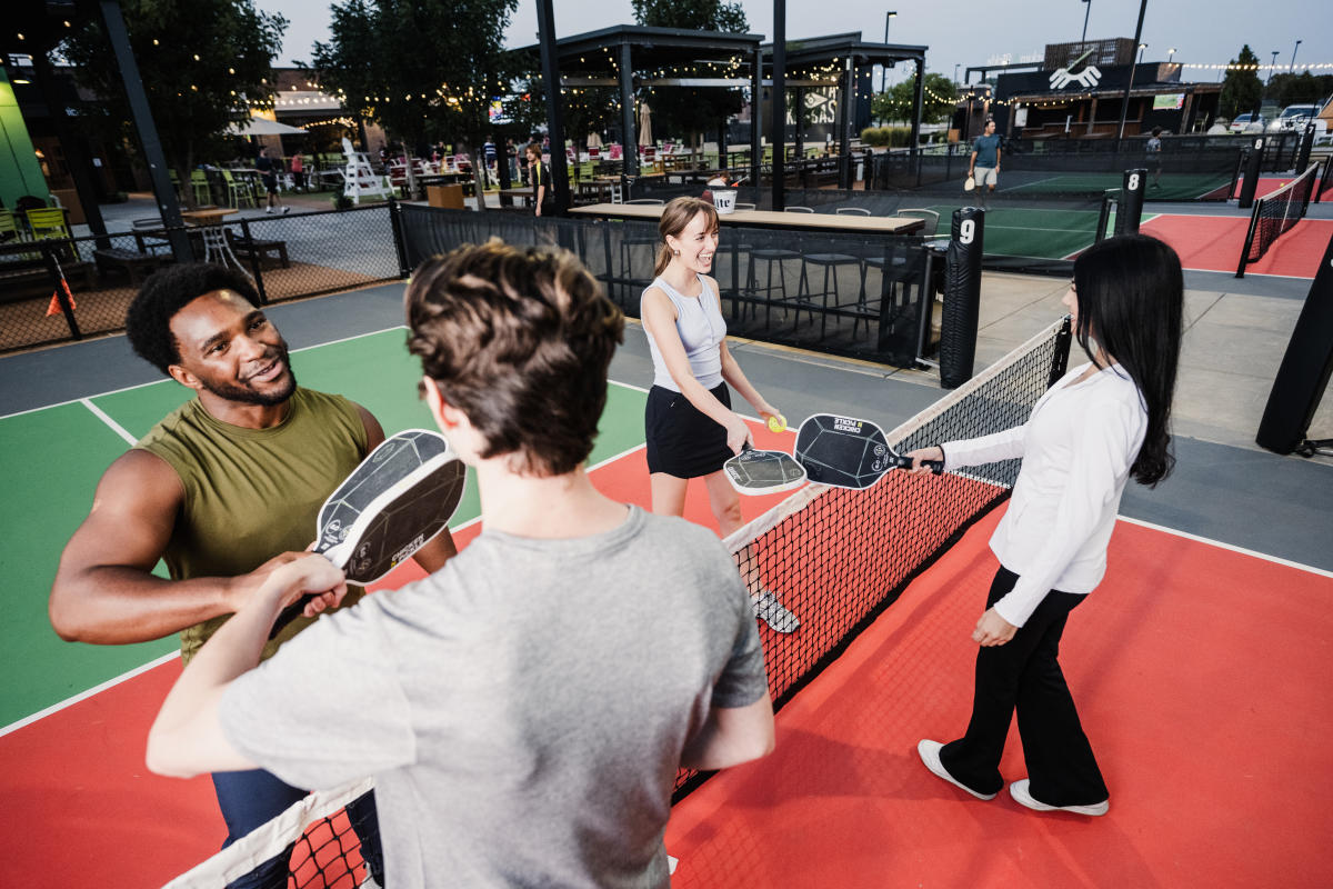 Two man and two women prepare to play a game of pickleball at Chicken N Pickle.