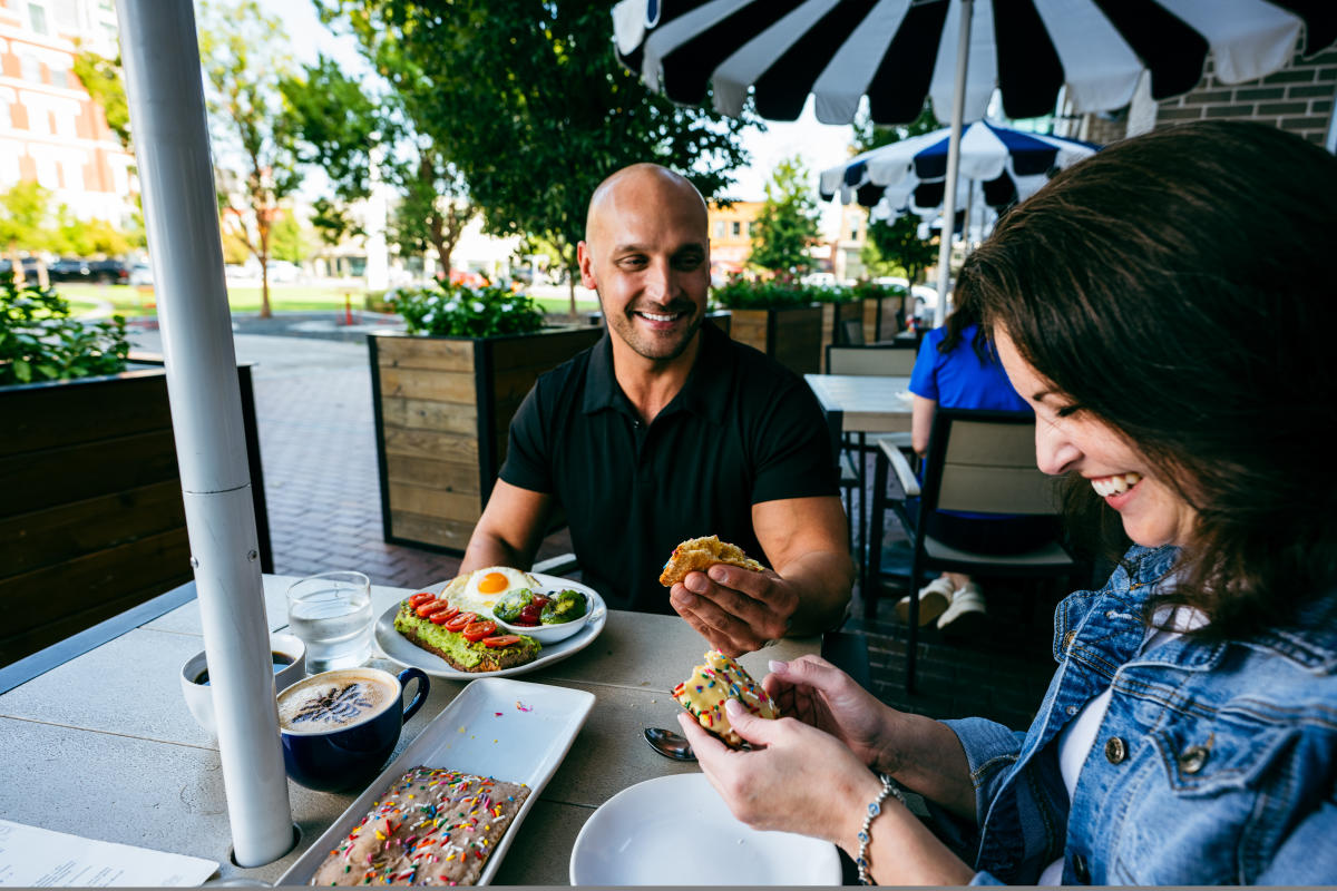 A man and woman enjoy a meal on the patio at HomeGrown