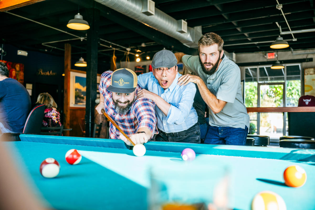 Three men watch a game of pool at The Monarch in Wichita.