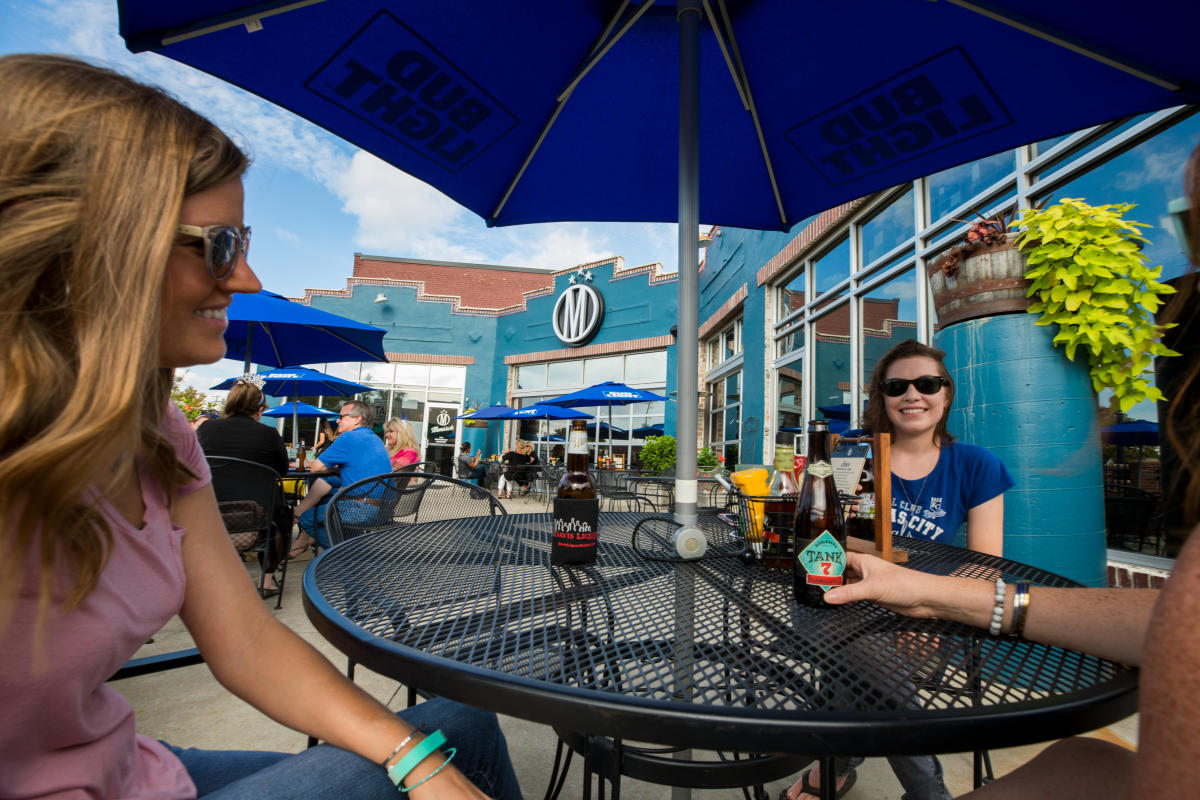 Three people enjoy drinks on the patio at Monarch