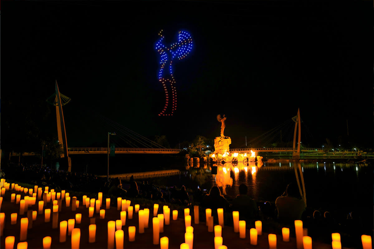 Drones create an image of the Keeper of the Plains over the Keeper of the Plains at night as the fire pots are illuminated at the Drone Light Festival in Wichita.