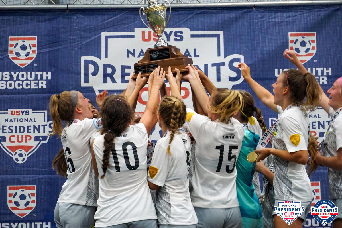 A young team of girl soccer players hug and celebrate after their US Youth Soccer Presidents Cup win