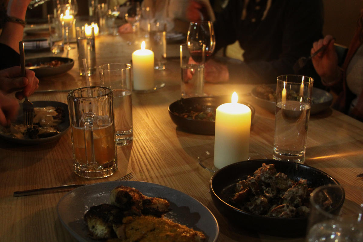 Lit candles illuminate a table full of food at First Mile Kitchen in Wichita