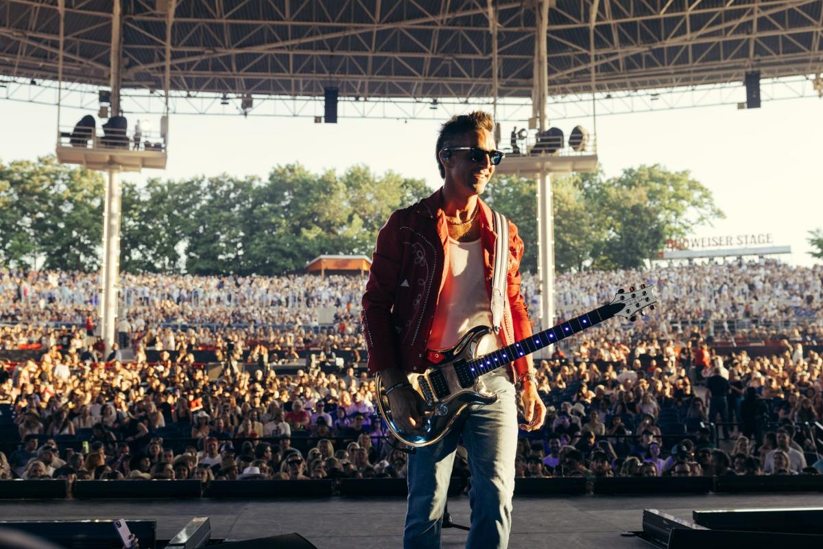 Country singer Jake Owen is photographed while on stage during a concert with the audience in the background.