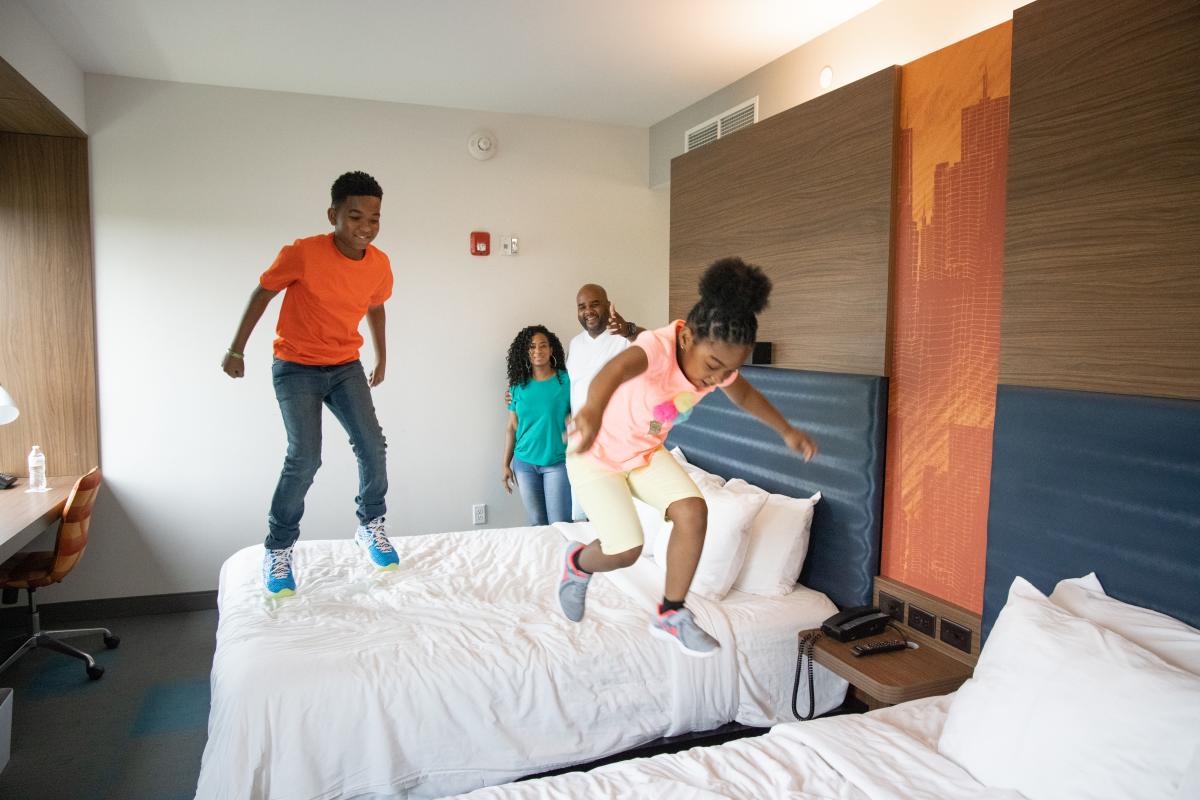 Two children jump on beds in a hotel room in Wichita, KS