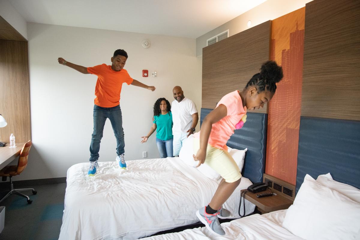 Young kids jump on hotel beds