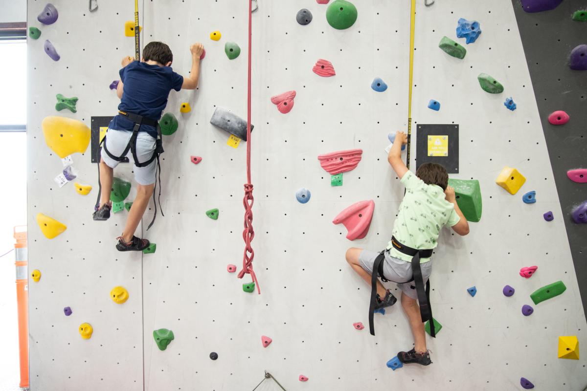 Two boys climbs a rock wall at Bliss Climbing and Fitness