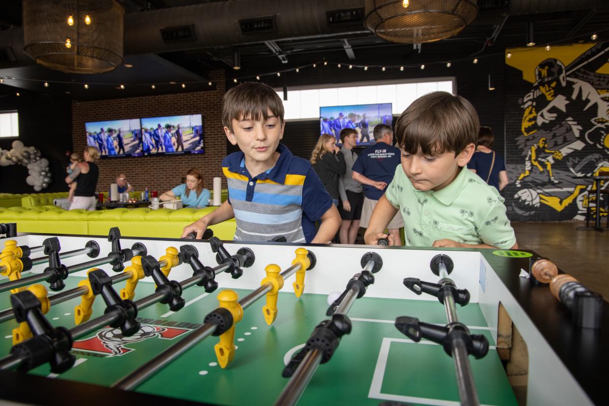 Two boys smile while enjoying a game of foosball at Chicken N Pickle