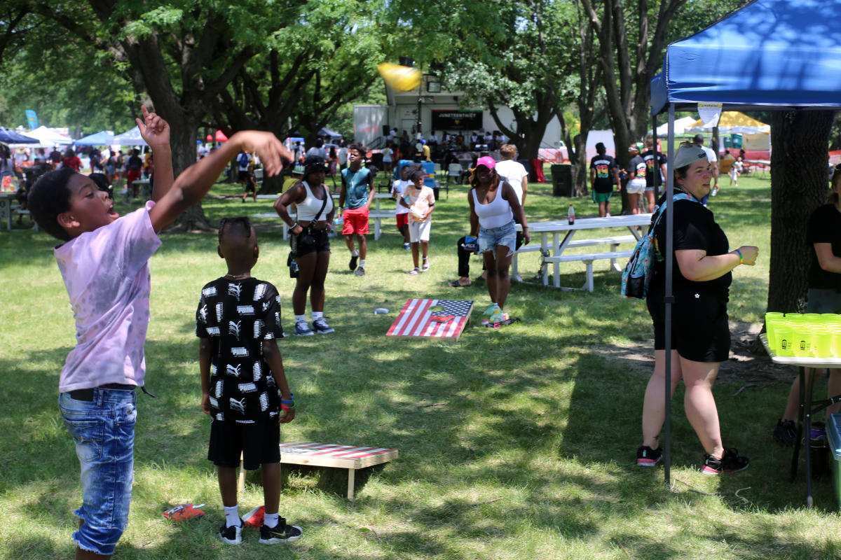 Kids play a game of cornhole during the JuneteenthICT Celebration