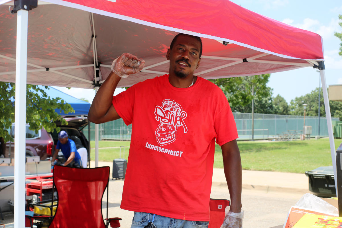 A man poses under a tent during the Carl Brewer Cookoff at the JuneteenthICT Celebration