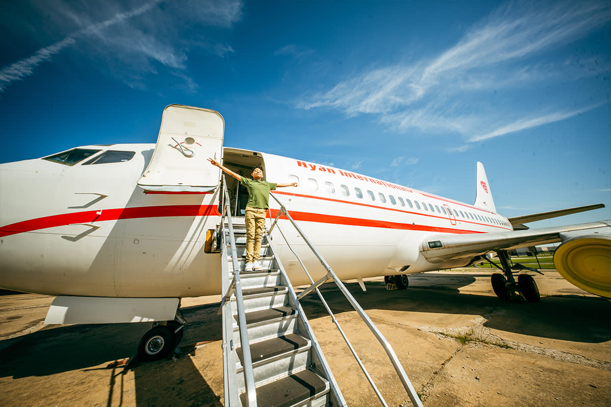 A boy smiles while facing the sun on the top of the steps of Ryan International aircraft at Kansas Aviation Museum in Wichita