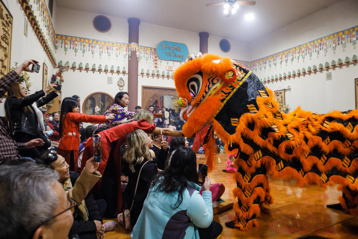People gather around a person in a dragon costume during a Lunar New Year celebration