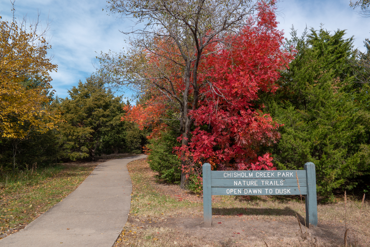 The trees turn orange and yellow in the fall near the entrance sign to Great Plains Nature Center