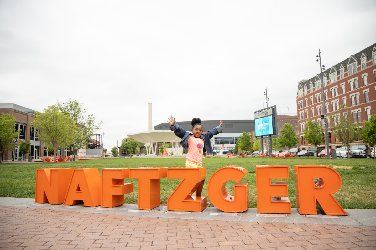 A young girl poses by the Naftzger Park sign at Naftzger Park