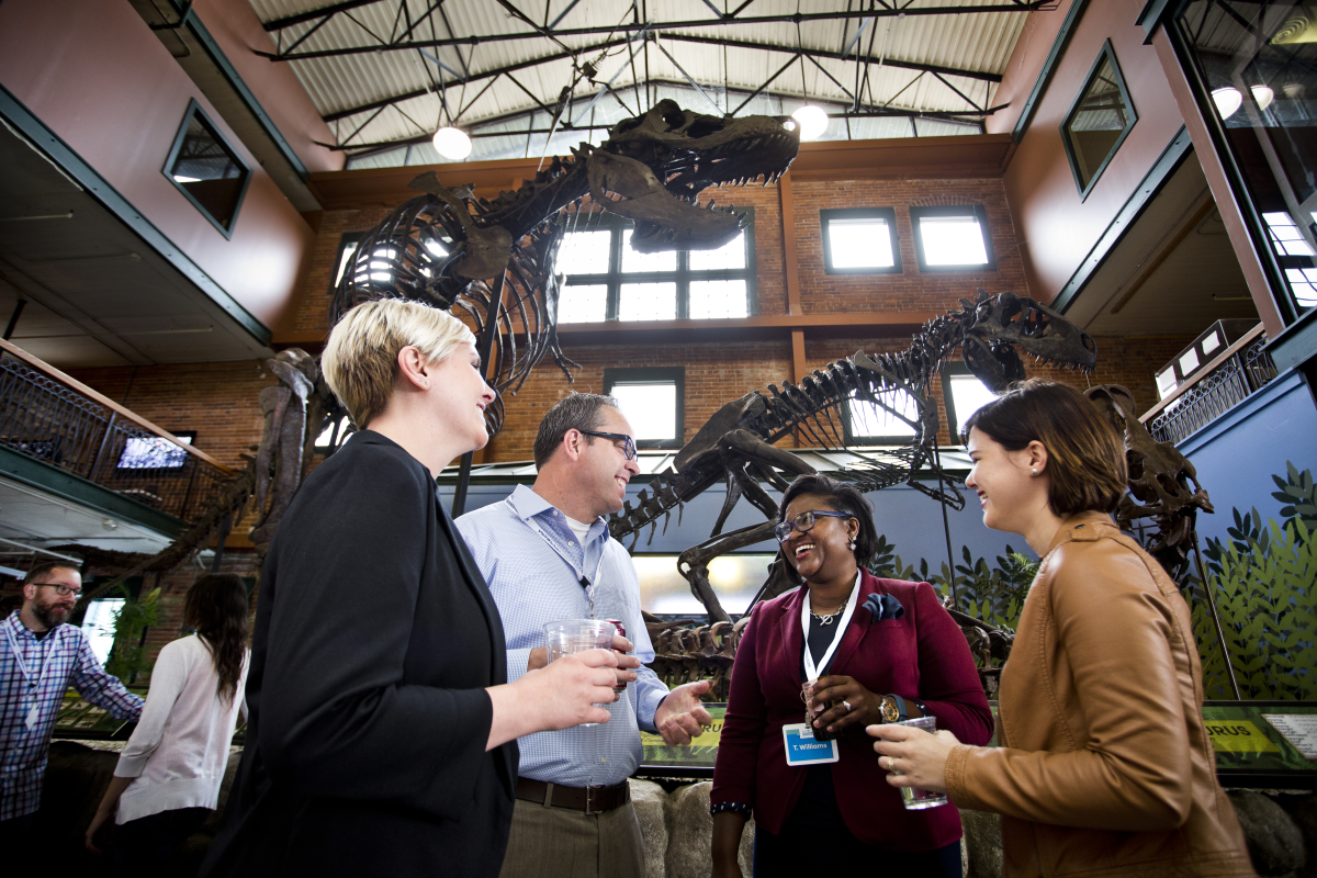A group meets underneath a T-Rex skeleton at Museum of World Treasures