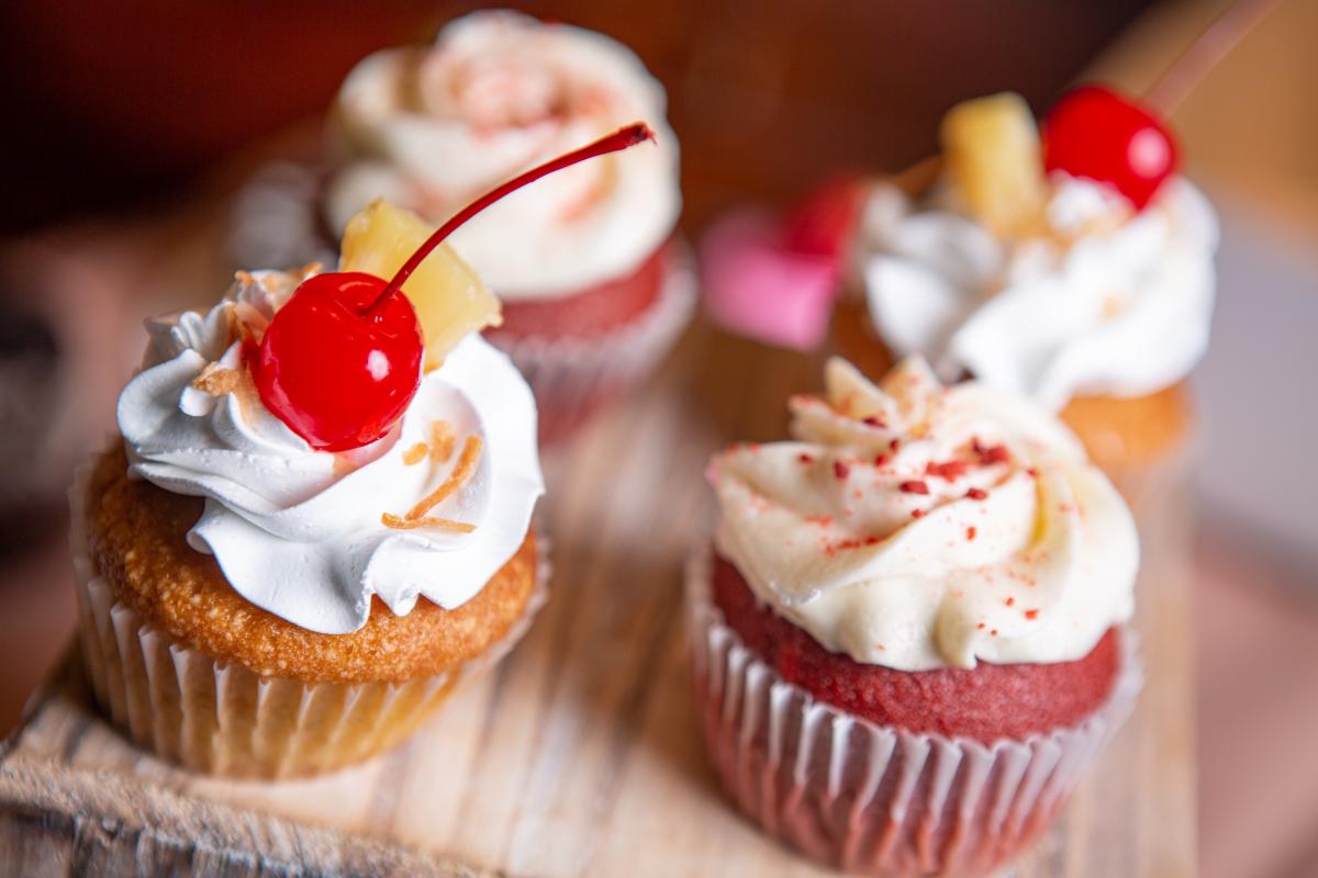 Four cupcakes topped with frosting, sprinkles and cherries sit on display at Monica's Bundt Cake