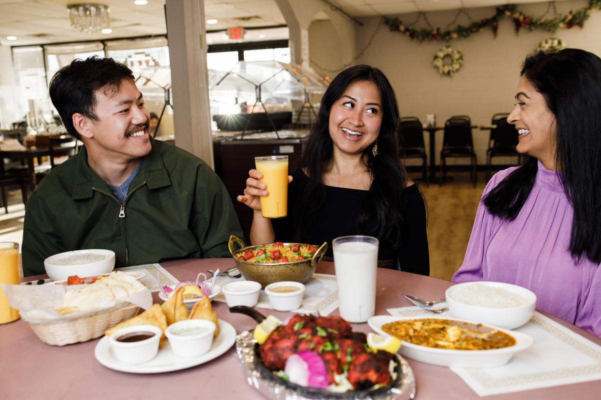 Three people smile while they dine at New Paradise restaurant in Wichita