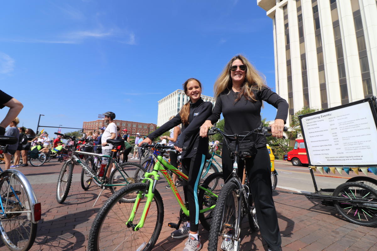 A woman and her daughter pose on their bicycles in downtown Wichita