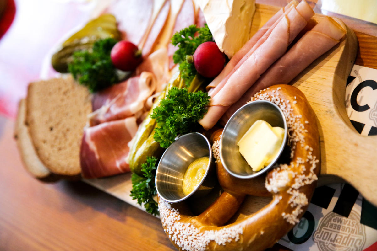 A pretzel and meats are served on a board at Prost