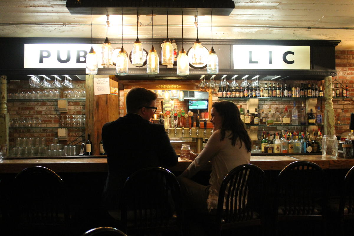 A man and woman talk at the bar inside Public