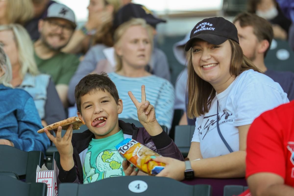 A young woman and small boy pose smiling for the camera while at a Wind Surge game