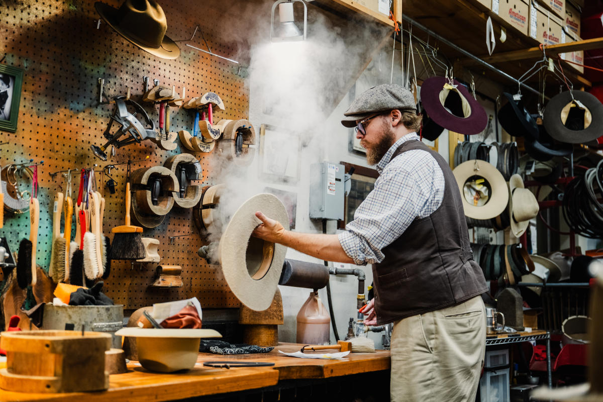 A man steams a hat during the fitting process at Hatman Jack's.