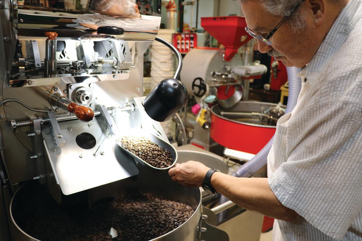 A employee at Spice Merchant scoops up roasted coffee beans