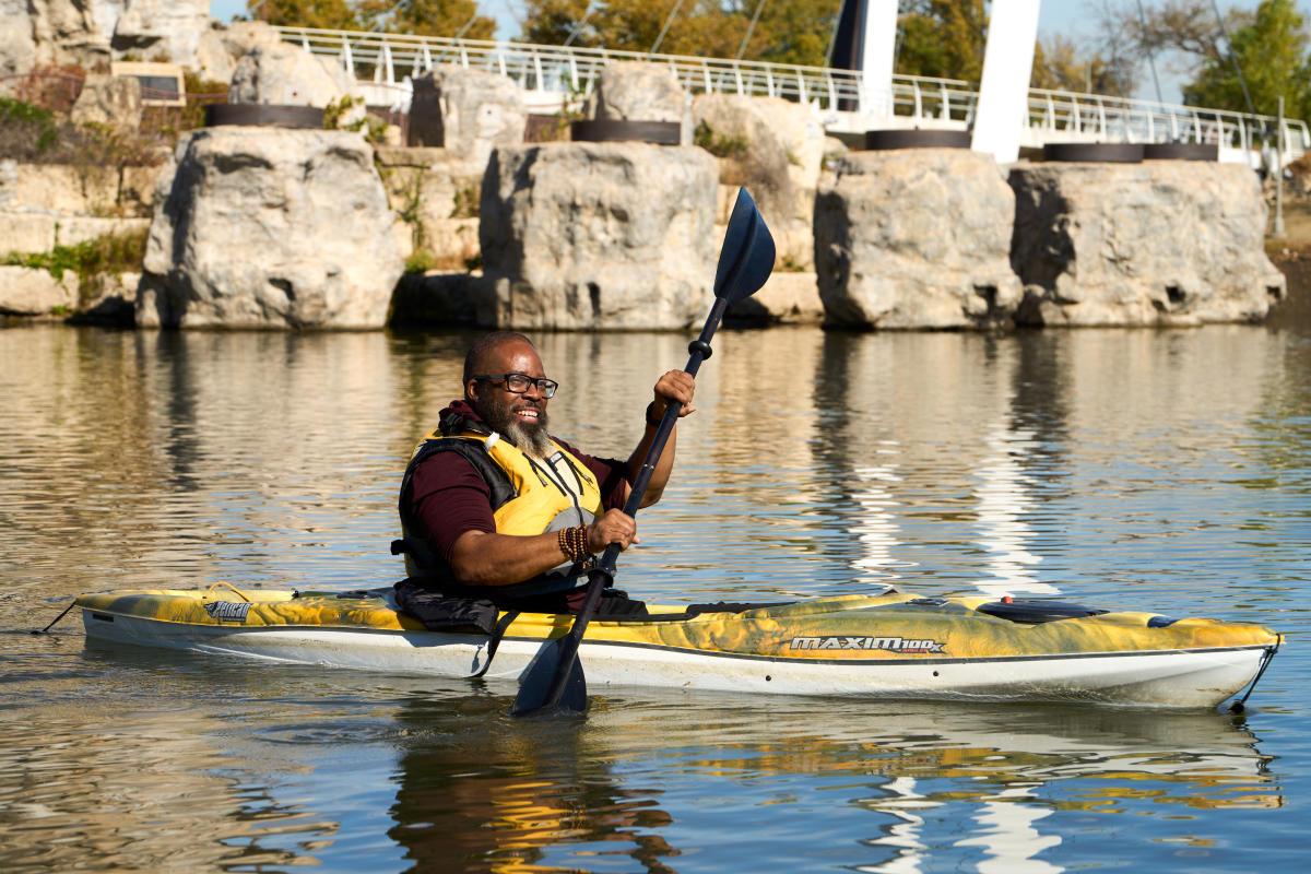 A man kayaks on the Arkansas River near the Keeper of the Plains