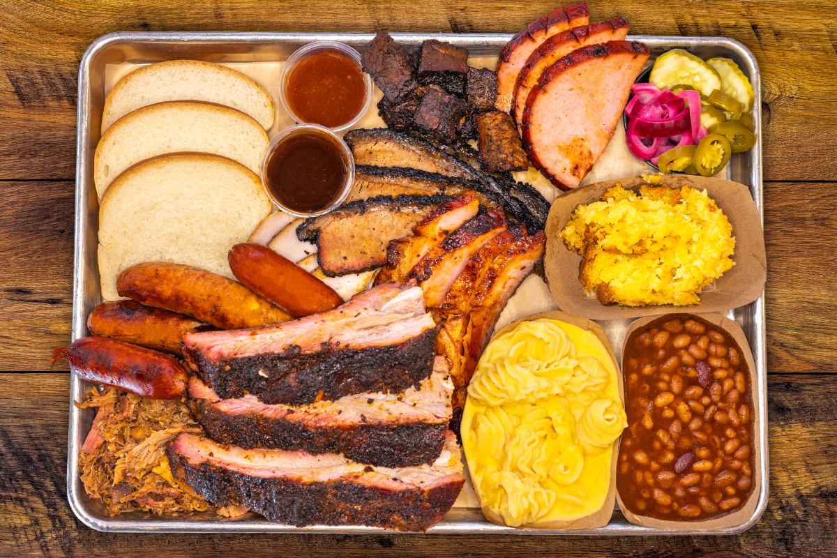 A variety of meats and homemade sides are served on a metal tray at Station 8 BBQ.